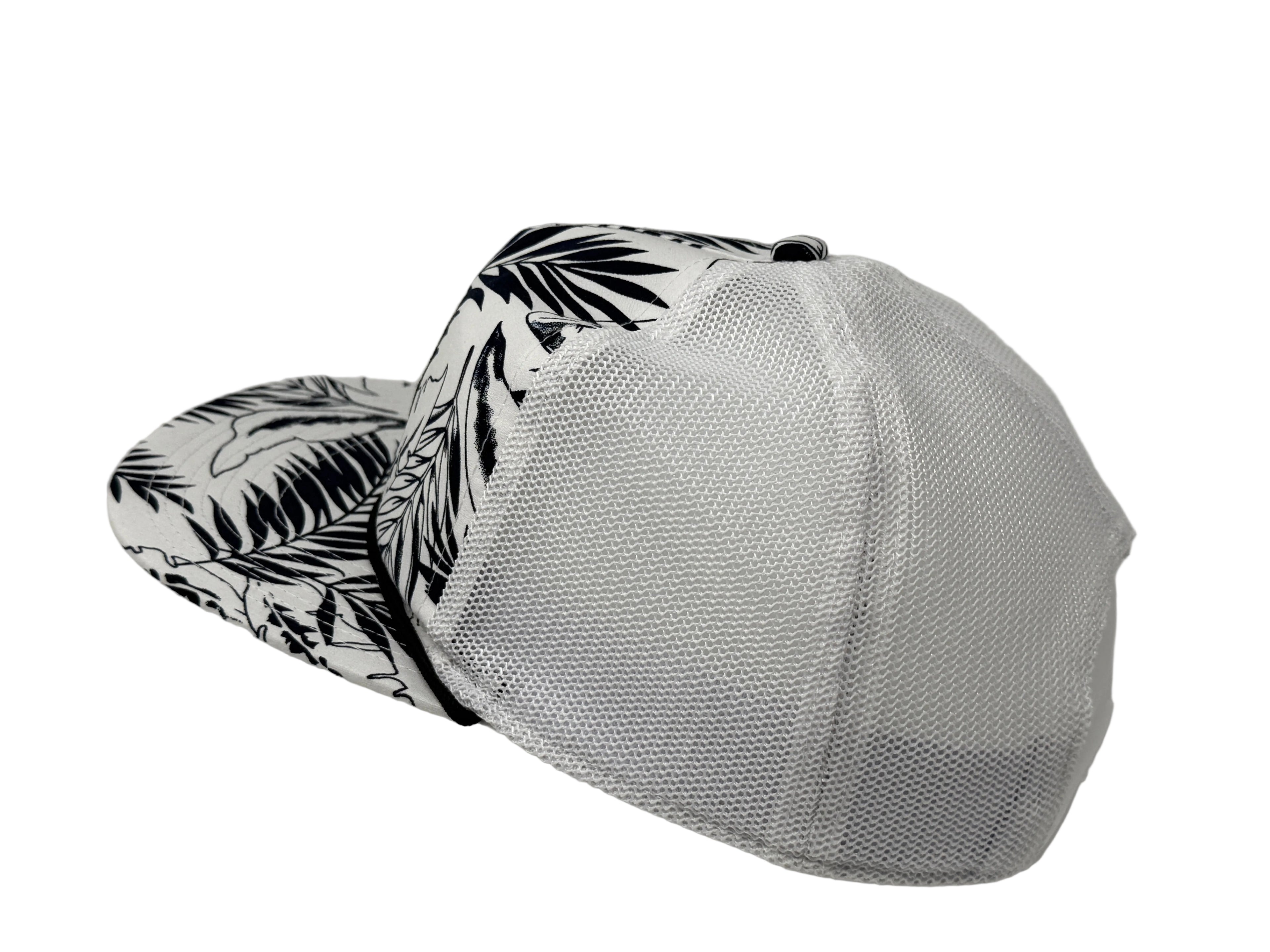 White cap with black leaf pattern on visor against a gray background
