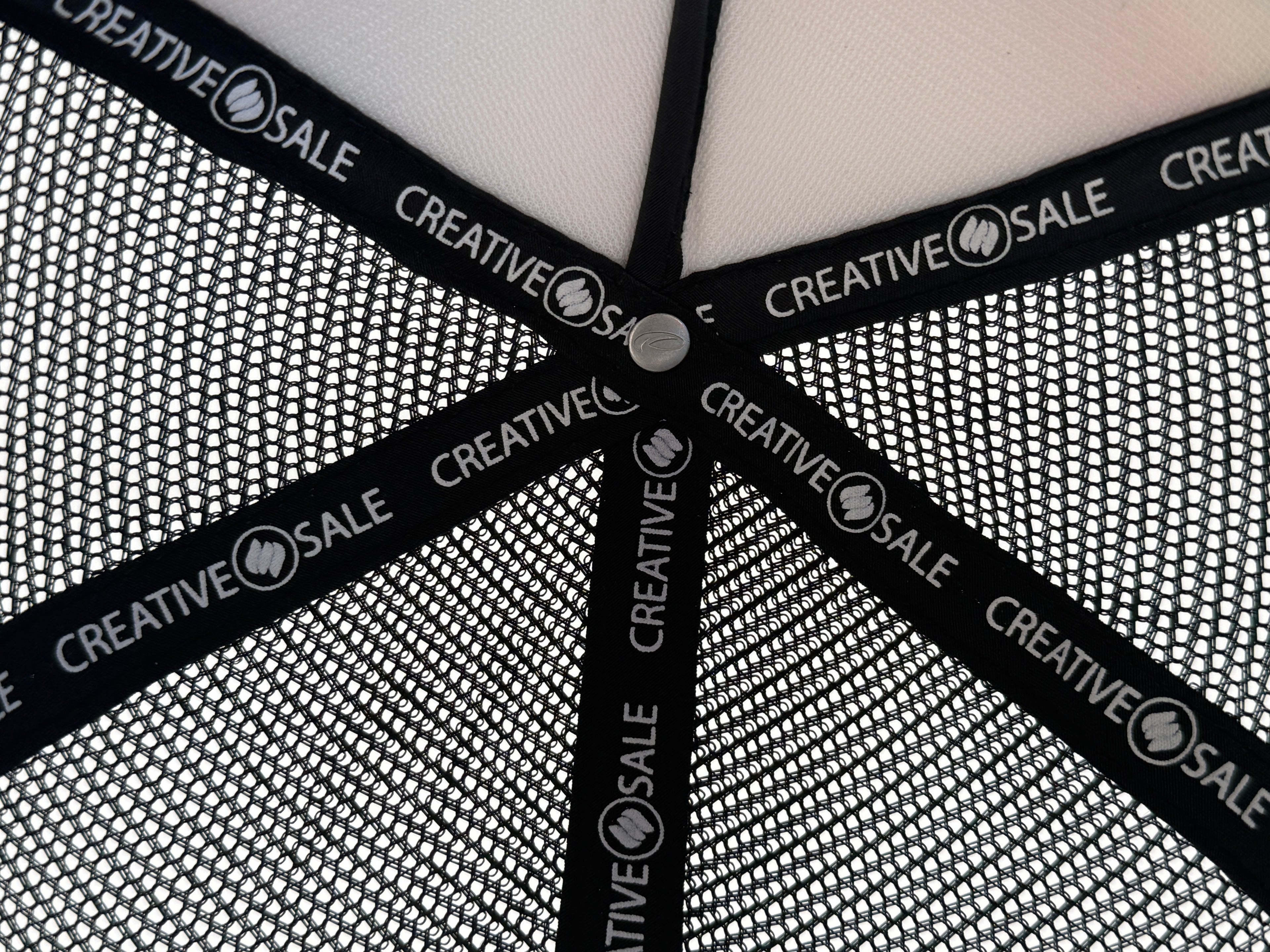 Close-up of a black cap with mesh back and 'Creative.Sale' branding.